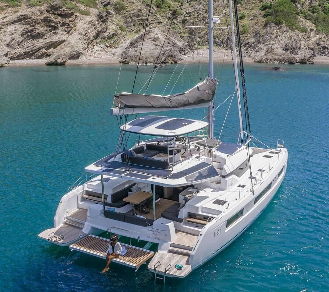 Een zeilboot met een afgedekt dek, een zitgedeelte en een persoon die voorin staat.