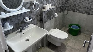 Un baño con lavamanos, inodoro, ducha y espejo.