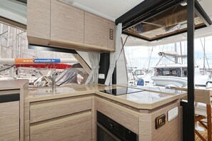 Eine moderne Küche mit Holzschnitzereien, einer schwarzen Arbeitsplatte und Blick auf den Yachthafen.