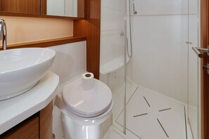 Een badkamer met een witte wastafel, toilet en douche.