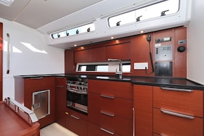 Een kleine keuken met een fornuis, oven, magnetron en een kleine koelkast.