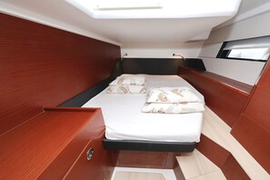 Een ruimtelijk, goed verlicht hokje met een bed, opbergladen en een raam.