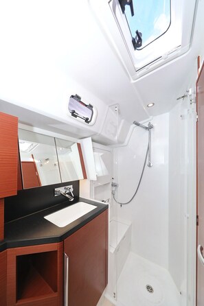 Een moderne badkamer met een douche, wastafel en spiegel.