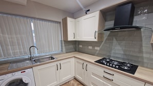 A modern kitchen with a built-in washing machine, stainless steel sink, and a gas stove. - Elysea Haven 3 Bedroom house, newly renovated (Leeds)
