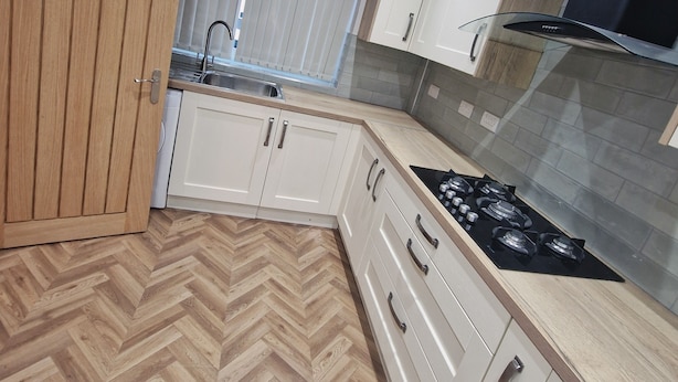 A modern kitchen with wooden cabinets, a herringbone floor, a gas stove, and a window with blinds. - Elysea Haven 3 Bedroom house, newly renovated (Leeds)