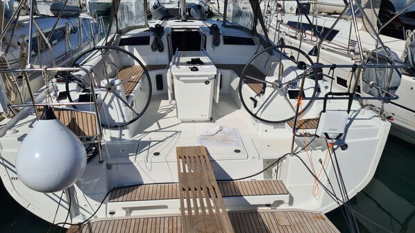 Marina com vários barcos atracados, destacando decks de madeira, volantes e diversos equipamentos de navegação.