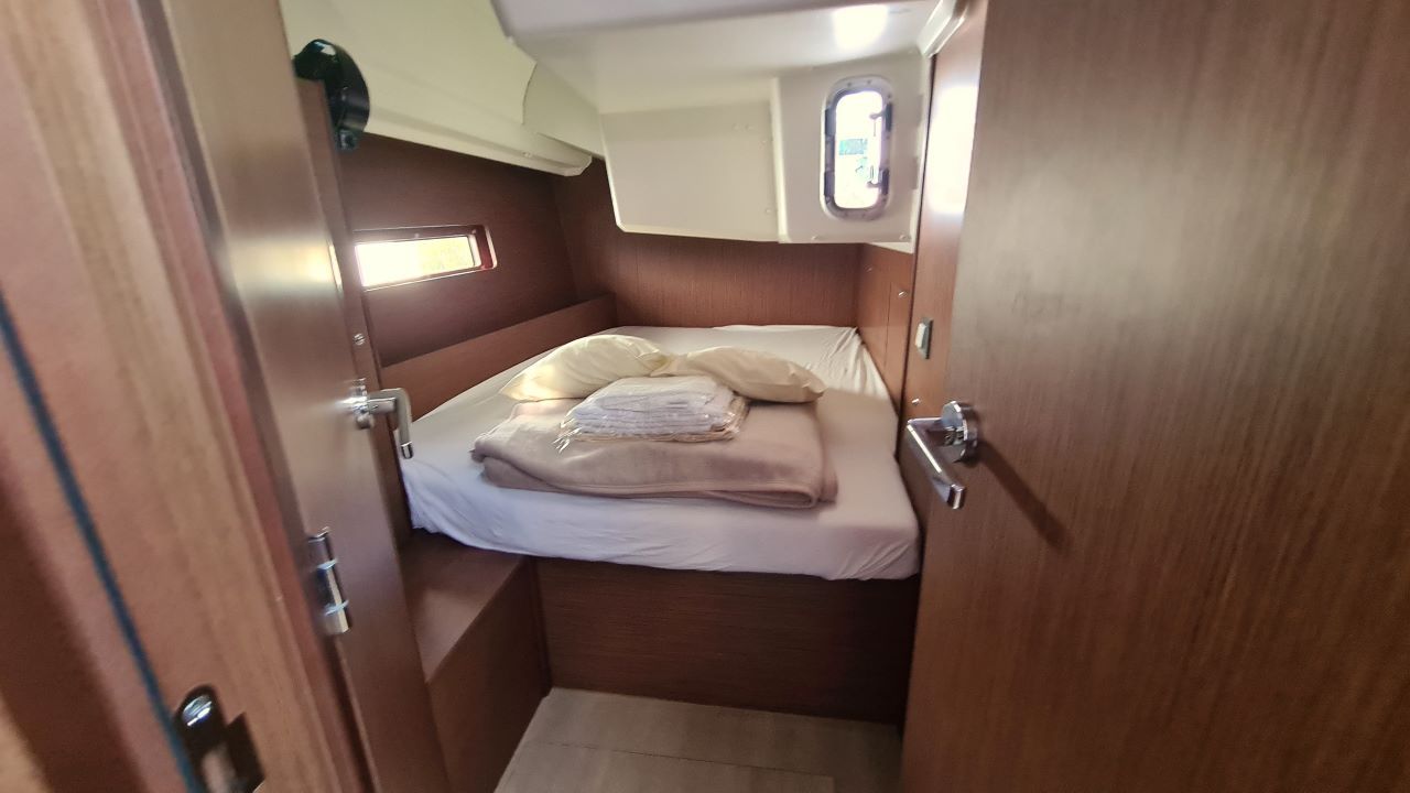 A compact, well-lit cabin with a bed, a small window, and a door.
