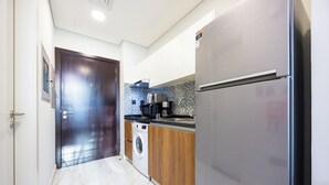 Una cucina compatta con lavatrice, frigorifero e forno a microonde.