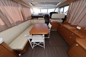 A compact RV interior with a dining area, seating, and a small kitchenette.