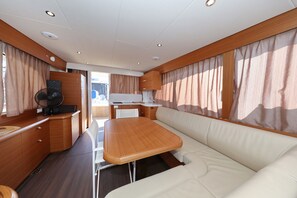 A compact RV interior with a kitchenette, a dining area, and a seating area.