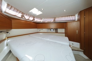 A compact boat cabin with a bed, wooden cabinetry, and a skylight.