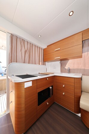 A compact kitchenette with wooden cabinetry, a countertop, and a sink. - Sun-Kissed Sailing Adventure in Zadar, Croatia (Biograd na moru)