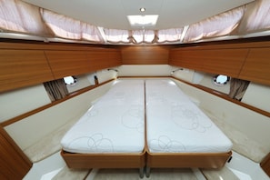 A compact, well-lit interior with a central bed, wooden cabinetry, and small windows. - Sun-Kissed Sailing Adventure in Zadar, Croatia (Biograd na moru)