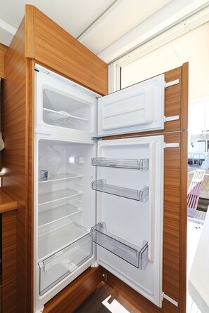 Eine moderne Küche mit integriertem Kühlschrank, Holzschränken und einer klaren Glastür.