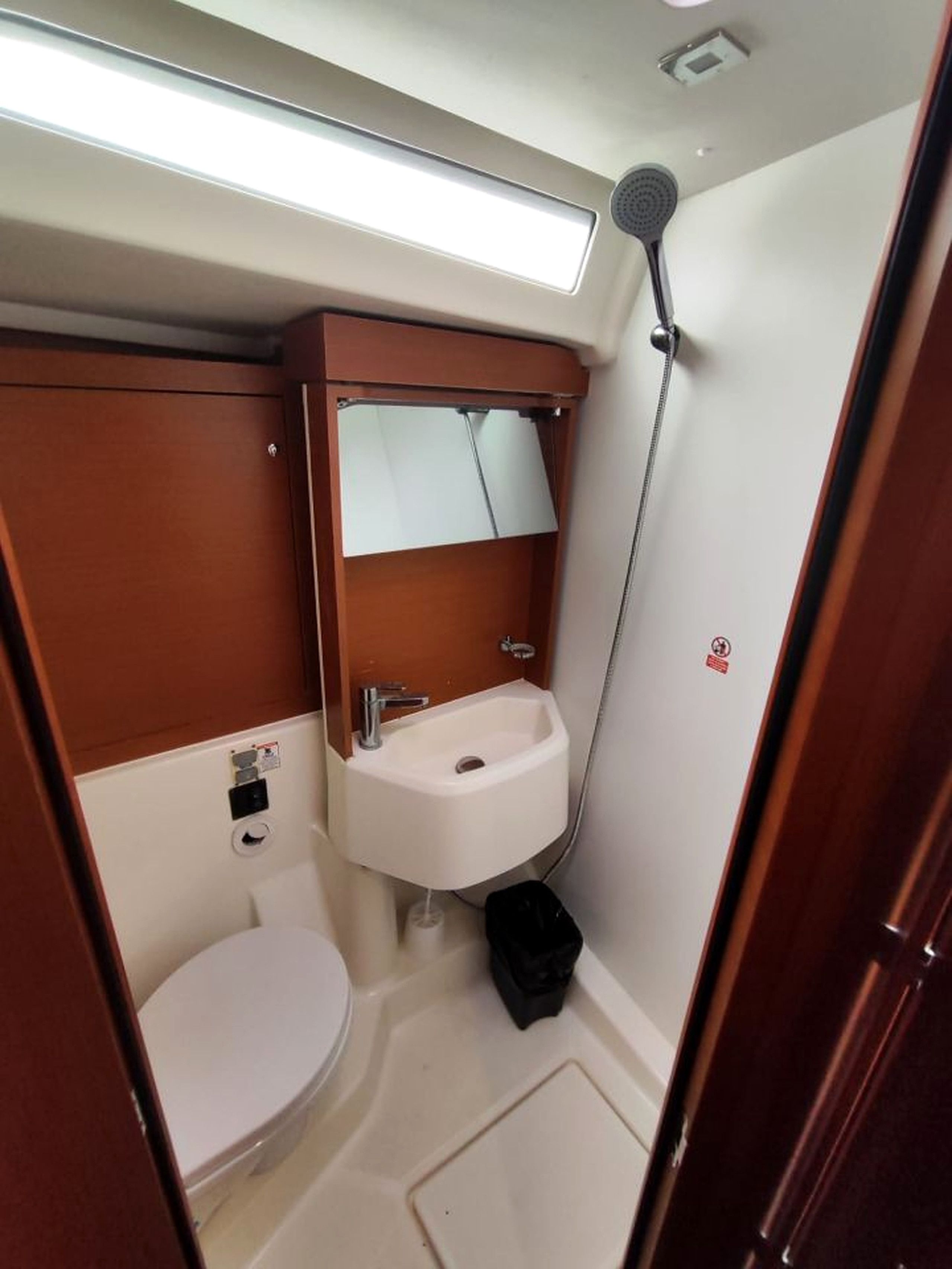 Et lille badeværelse med toilet, vask og brusebad.