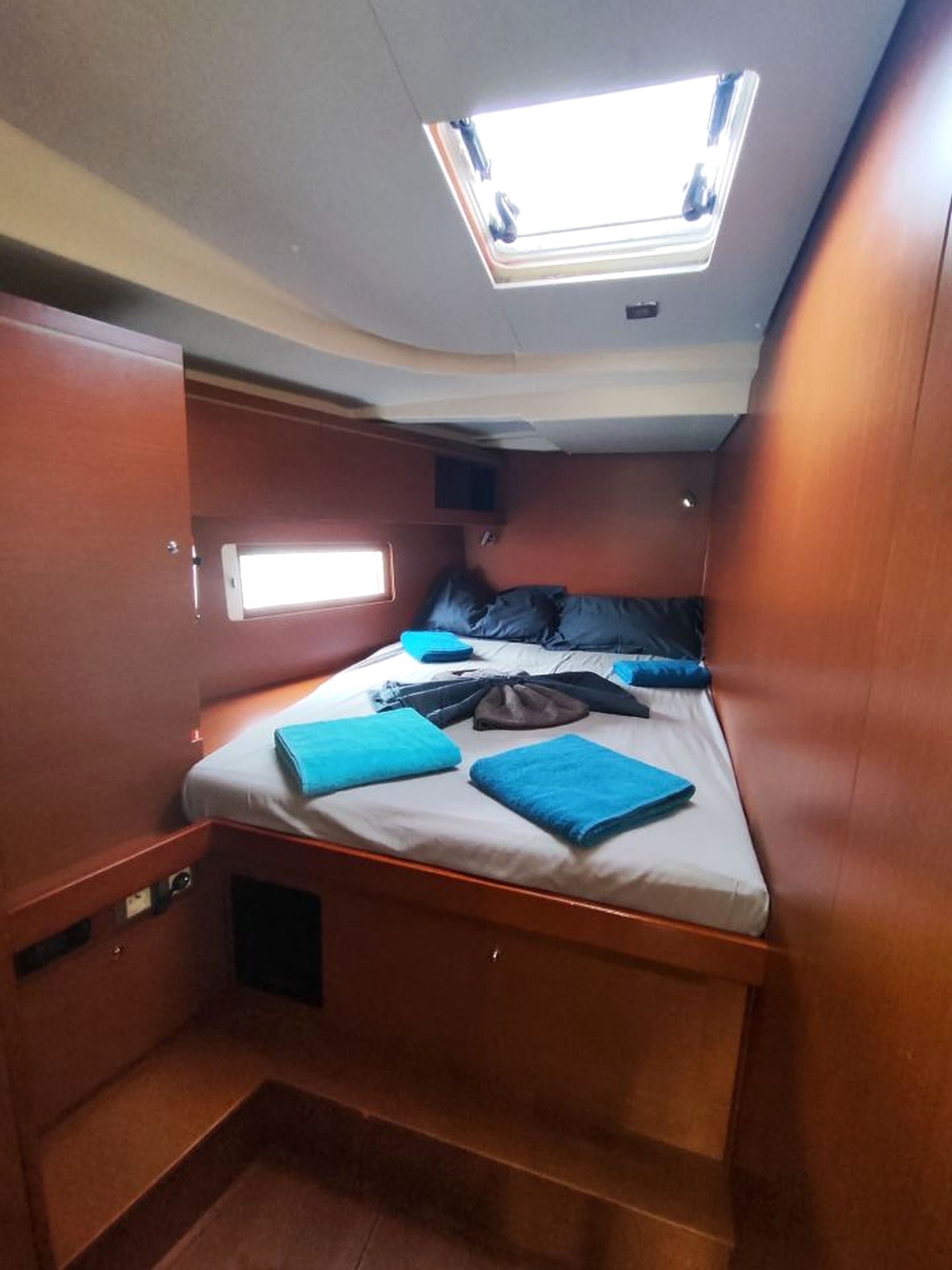 Una cabaña compacta con una cama, tragaluz y una pequeña ventana.