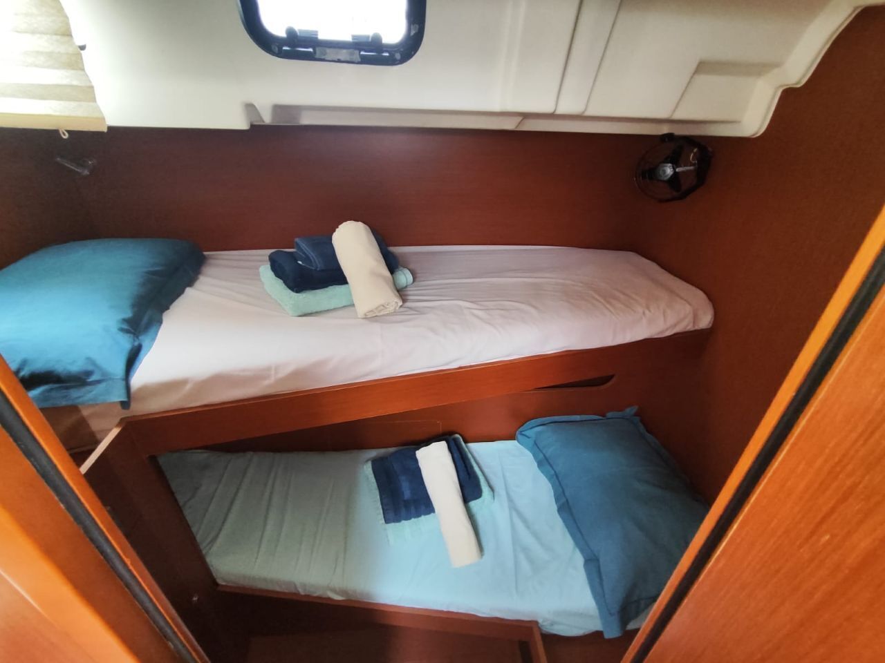 Interior de una caravana compacta con dos literas, un ventanal pequeño y una cocina de dimensiones reducidas.