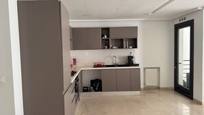 Eine moderne Küche mit grauen Schränken, einem eingebauten Backofen und einer schwarzen Kaffeemaschine.