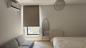 Ein Schlafzimmer mit Sofa, Bett, Heizkörper, Fenster mit Blick und Deckenventilator.