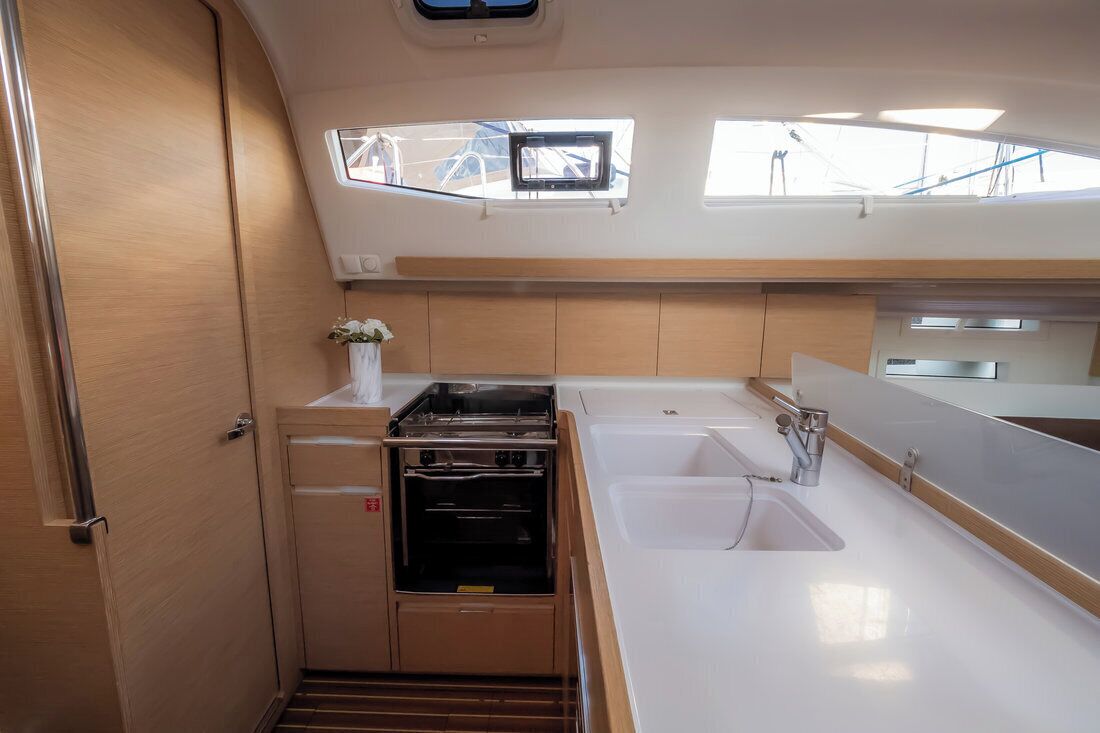 Cocina compacta con horno empotrado, un lavamanos y una ventana sobre la encimera.