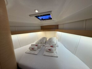 Eine Yachtt-Kabine mit Bett, Schiebedach und kleinem Fenster.
