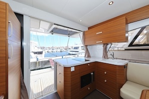 A compact galley with a sink, wooden cabinetry, and a view of the marina. - Sun-Kissed Sailing Adventure in Zadar, Croatia (Biograd na moru)