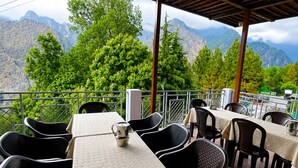 Terraza al aire libre con mesas y sillas, con vistas a un paisaje montañoso.