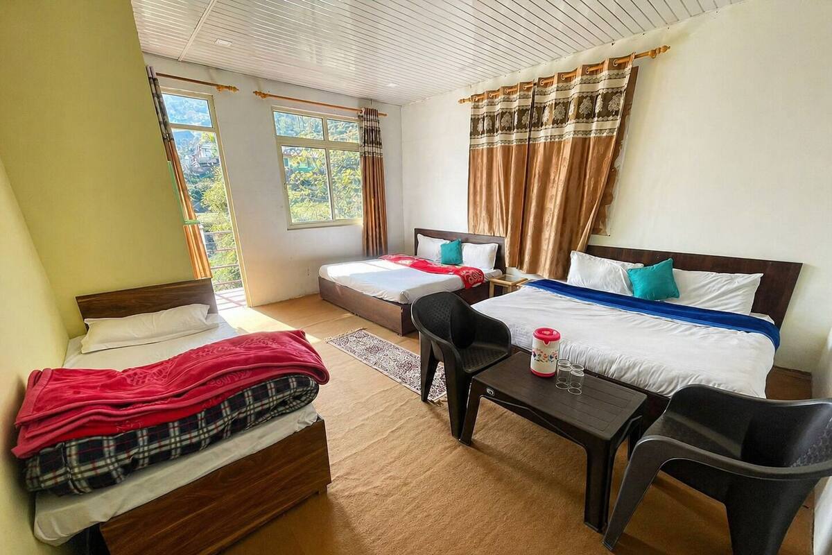 Une chambre avec deux lits, une petite table, une chaise et une fenêtre avec des rideaux.