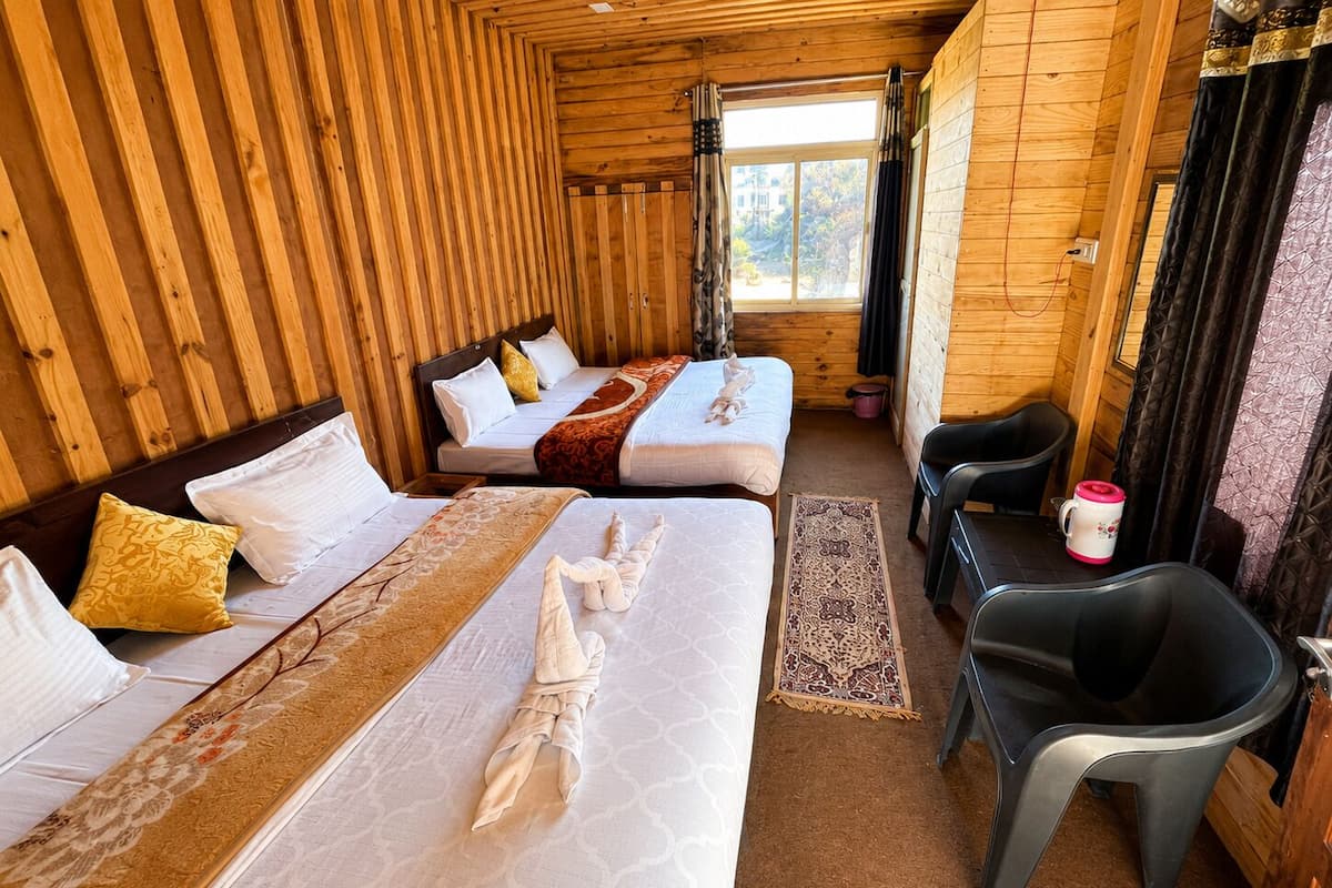 Une cabane en bois avec deux lits, un canapé, une chaise et une fenêtre.