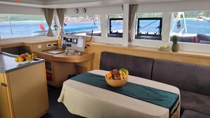 A compact cabin with a kitchenette, a dining area with a table and a bowl of fruit, and a sofa.