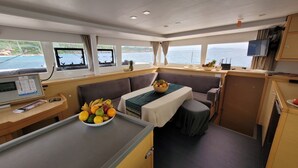 A compact cabin with a dining area, a small kitchenette, and a seating area with a view of the sea.