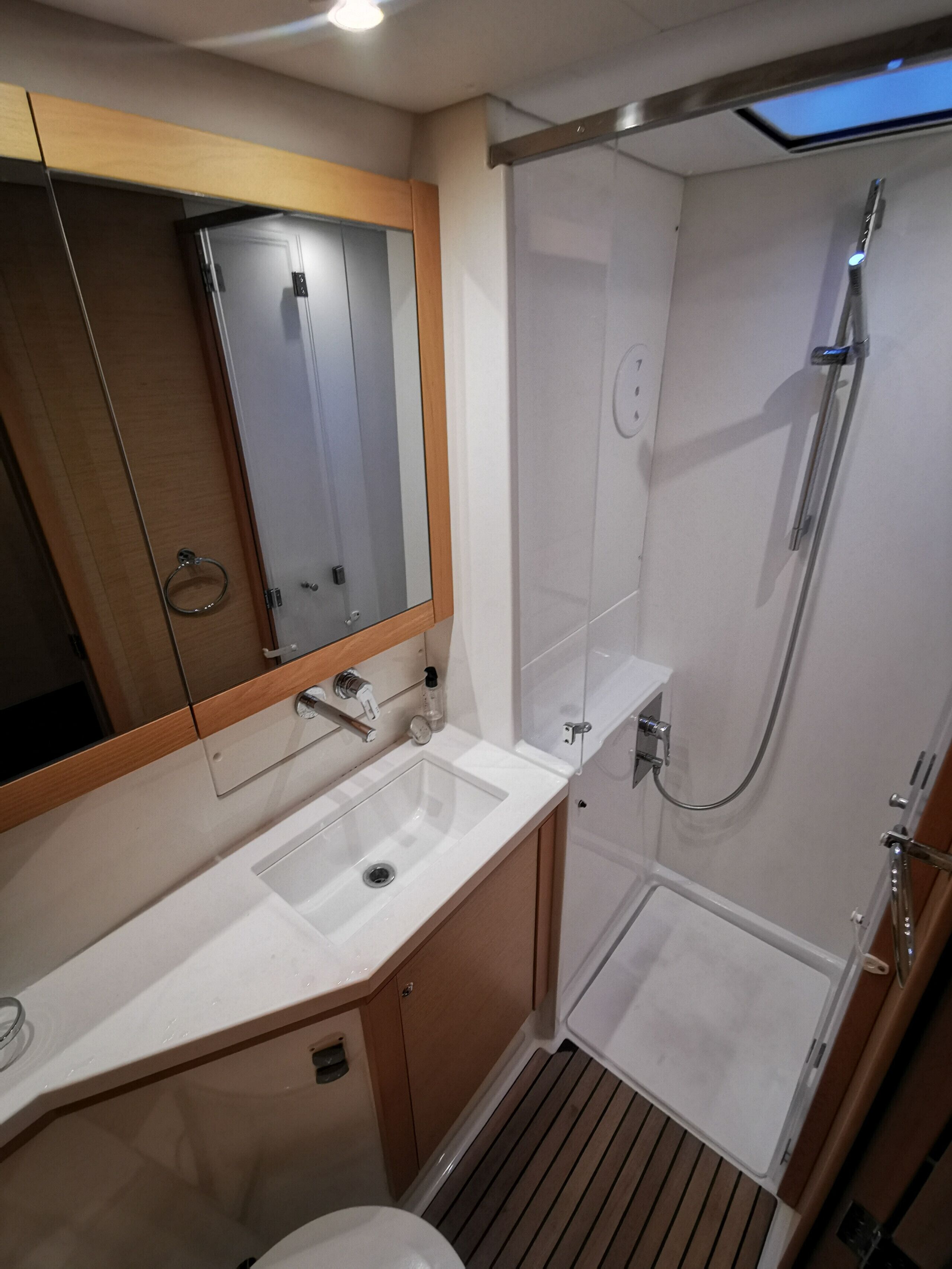 Une salle de bain avec un lavabo, un miroir, une douche et un plancher en bois.