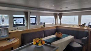 A cabin with a dining area, a control panel, and a view of the sea.