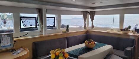 A cabin with a dining area, a control panel, and a view of the sea.