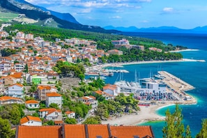 Un pueblo costero con un puerto deportivo, edificios de techos rojos y una playa.