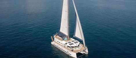 Un voilier doté d’une cabine et d’un espace sur le pont, naviguant sur une mer calme.