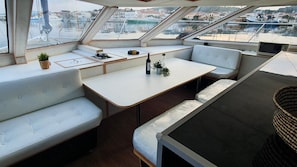 A yacht interior with a dining area, seating, and a view of the marina. - Sun-kissed Sailing Adventure in Split-Dalmatia, Croatia (Trogir)
