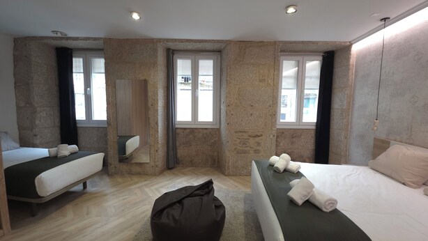 Una habitación de hotel con dos camas, un espejo grande y vistas al exterior a través de las ventanas.