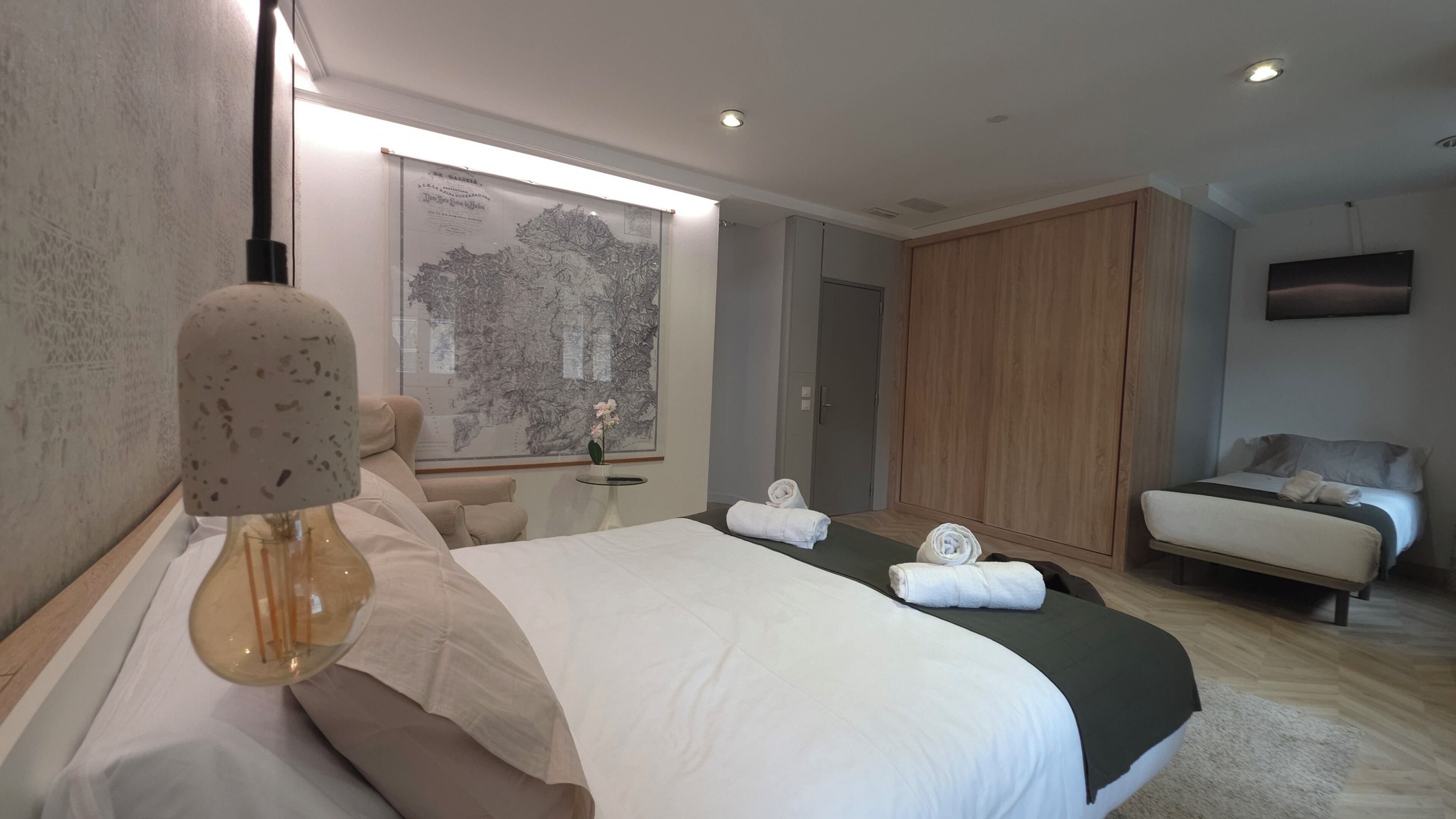 Une chambre d’hôtel moderne équipée d’un grand lit, d’un bureau, d’une armoire et d’un téléviseur fixé au mur.