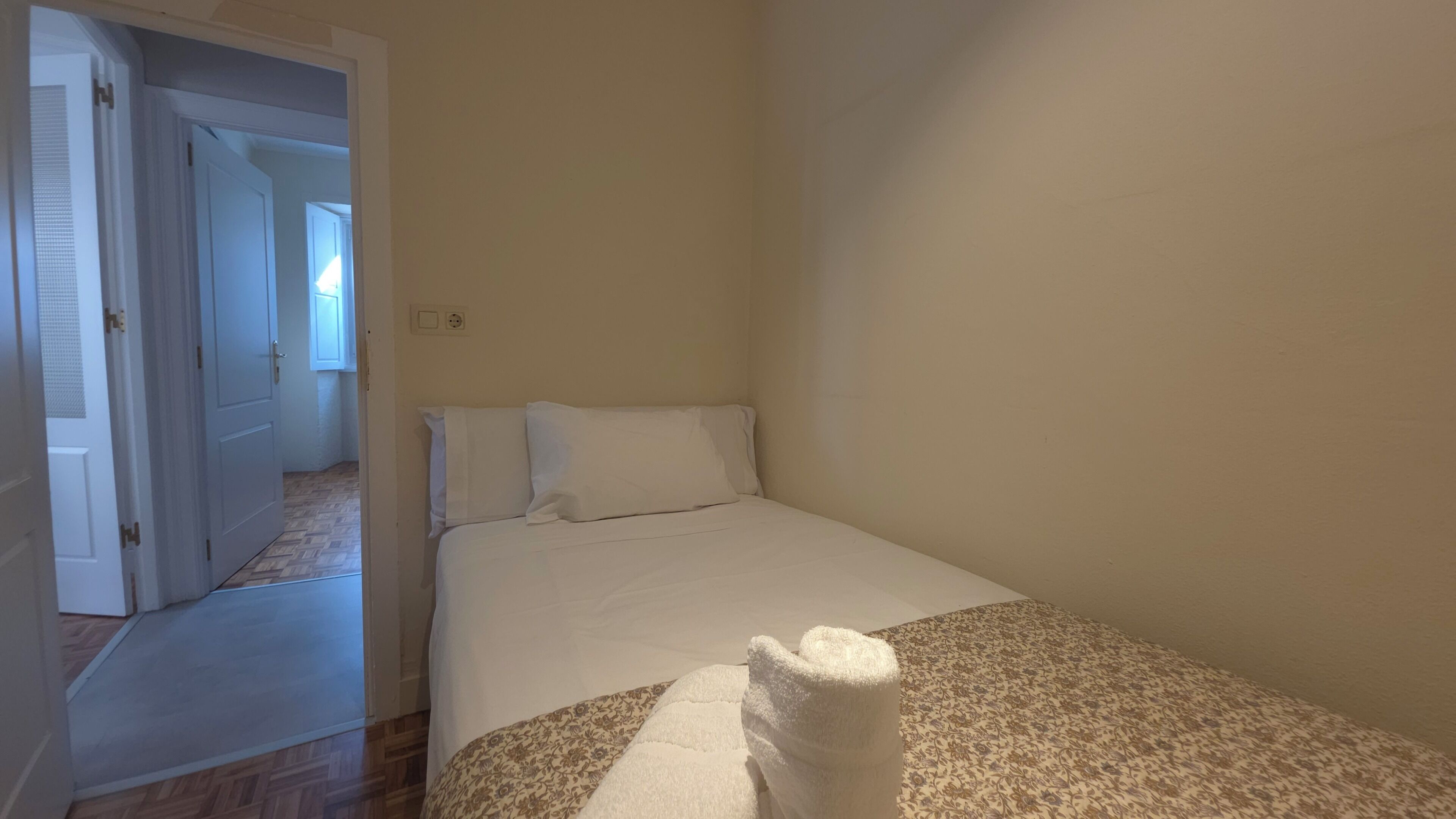 A bedroom with a bed, a door, and a patterned rug.