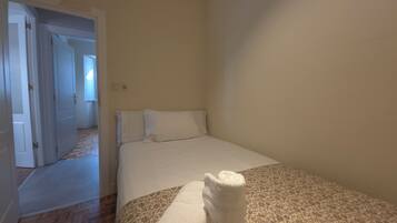 A bedroom with a bed, a door, and a patterned rug.
