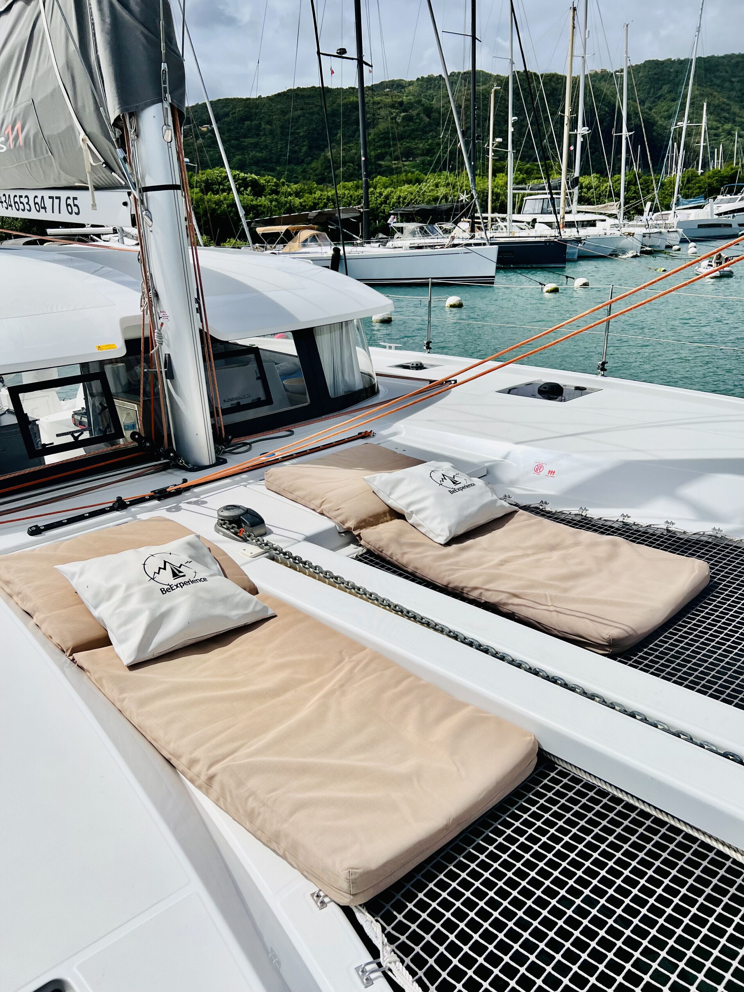 Ett däck på en lyxyacht med solstolar, ett skyddat område och en småbåtshamn i bakgrunden.