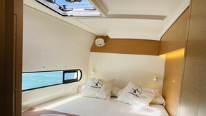 Una cabaña moderna con cama, almohadas y vista al mar a través de una ventana.