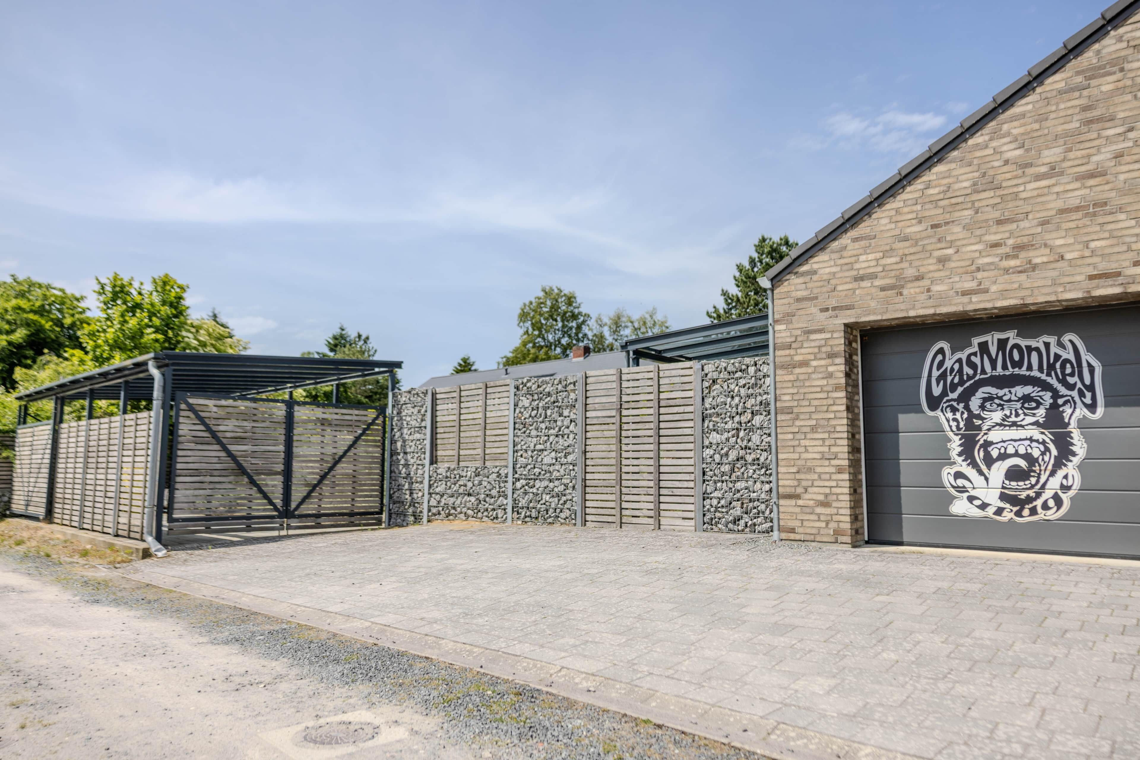 Un bâtiment doté d’une porte de garage portant l’inscription « GasMonk » et d’un espace extérieur abrité.