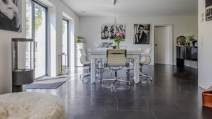 Una sala de estar moderna con comedor, ventanas amplias y obras de arte en las paredes.