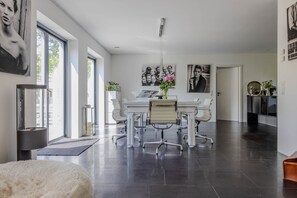 Ein modernes Wohnzimmer mit Essbereich, großen Fenstern und Kunstwerken an den Wänden.