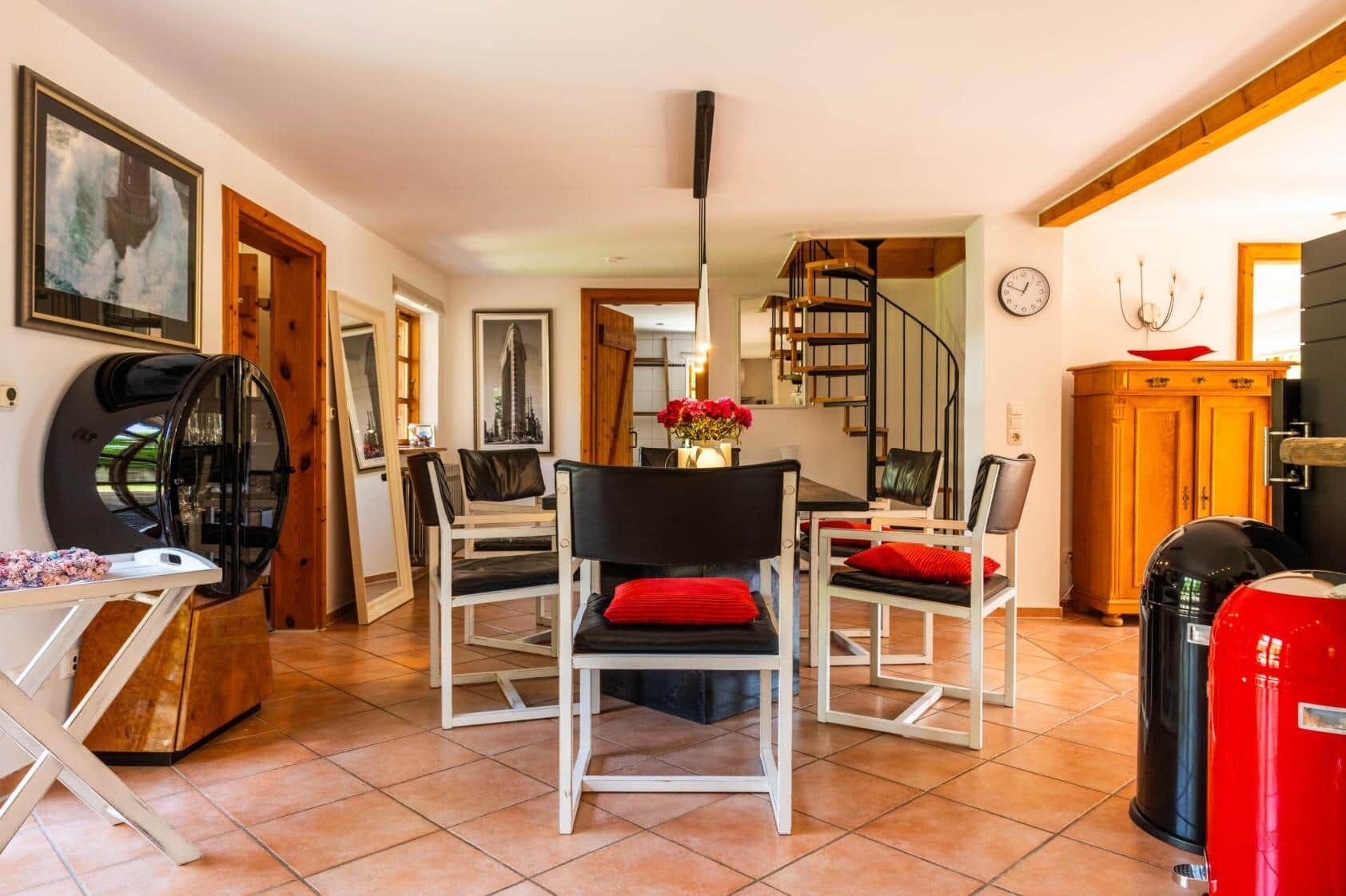 A dining area with a round table, chairs, and a staircase in the background.