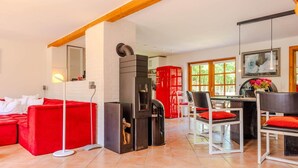 Ein modernes Wohnzimmer mit einem roten Sofa, einem Kamin und einem Essbereich mit Stühlen und einem Tisch.
