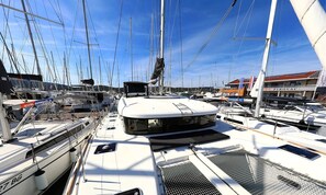 A marina with multiple sailboats docked, a covered area, and a building with signage. - Sibenik Sun-soaked Sailing: A Luxurious Croatian Voyage (Pirovac)