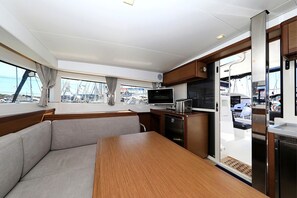 A modern interior with a dining area, kitchen, and large windows offering views of the marina. - Sibenik Sun-soaked Sailing: A Luxurious Croatian Voyage (Pirovac)